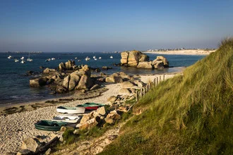 Calm scene between rocks and sea, with gentle waves and fine sand.