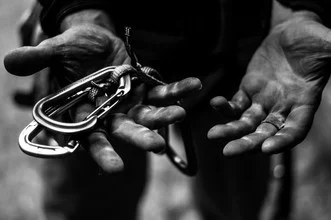 Photo art: Climber's hands gripping a rock, captured in black and white.