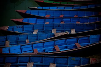 Fotografie von blauen Booten auf dem See in Nepal, friedliche Stimmung und sanfte Farben.