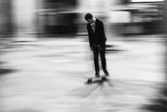 Boy in a black suit skateboarding on the street, relaxed and enjoying the moment.