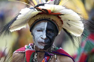 Portrait of a woman with traditional body paint and feathers in Papua New Guinea.