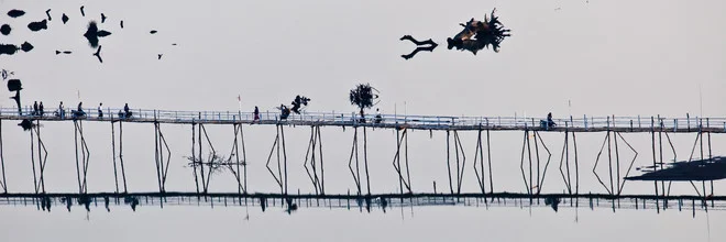 Charming bridge over calm water in Myanmar, surrounded by gentle morning hues.