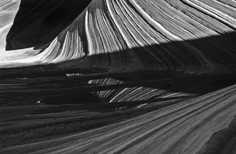 Fotokunst von Peter Fauland: Wellen aus Sandstein in der Wüste mit ruhiger Reflexion.