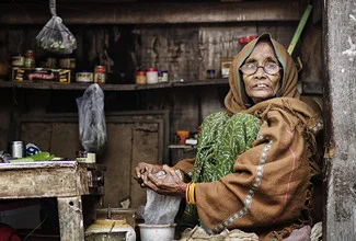 Portrait of a smiling saleswoman in Varanasi offering fresh produce.