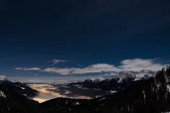 Night photo of Inntal with a starry sky and mountains in the background