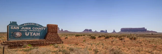 Photo art by Melanie Viola: panoramic view of Monument Valley with sign