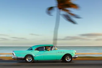 Photo of a vintage car in Cuba with palm trees and a sunset backdrop.