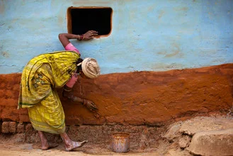 Hütte in Orissa, Indien: eine Frau vor einem lehmfarbenen, türkis gestrichenen Haus.