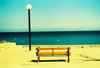 Seaside photo by Kathrin Schabelski: calm scene with bench by the sea in Greece.