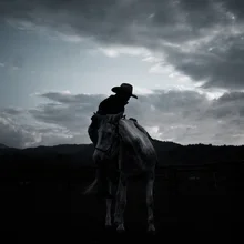 Silhouette eines Reiters vor Wolken, die eine ruhige Stimmung vermittelt.
