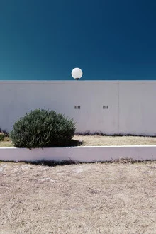 Fotokunst von Eva Stadler: einsame Laterne vor einer Trockenmauer mit Gras und Busch.