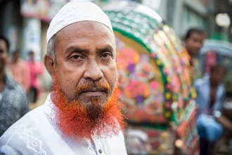 Porträt eines Mannes mit Bart in einer bunten Tuk Tuk-Rikscha in Dhaka