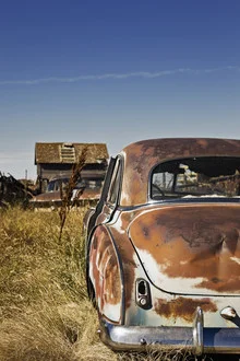 Rusty classic car in portrait format at a scrapyard, evokes nostalgia.