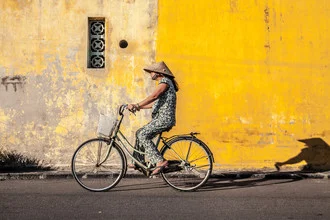 Photo of a cyclist in Hoi An, Vietnam, with shadow and yellow wall in the background