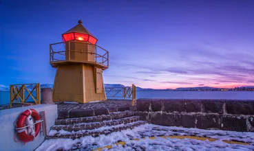 Photo art by Markus Van Hauten: lighthouse in Reykjavik at sunset over water and ice.