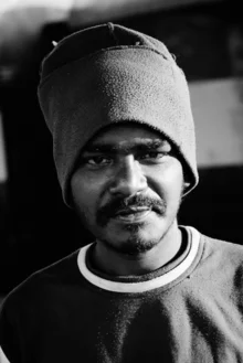 Portrait of a man with a hat in Udupi, India, featuring warm colors and a friendly mood.