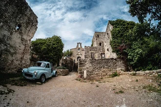 Photo art of a blue car in front of an urban ruin under a clear sky.