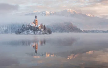 Photo art by Aleš Krivec: serene view of Lake Bled in winter at sunrise