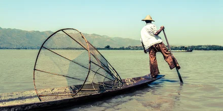 One-legged fisherman in Myanmar: fishing boat on calm water at sunrise