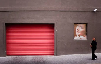 Photo art by Jac Kritzinger: Woman in front of a red door in Cape Town with a calm expression.
