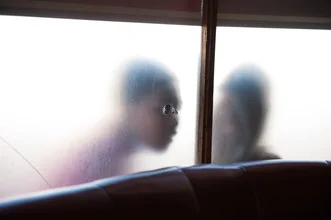 Photo art by Jac Kritzinger: boys peeking through a hole in a restaurant window