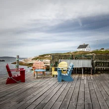 Fotokunst von Marie Joelle Nimmesgern: bunte Stühle auf einer Terrasse am Meer.