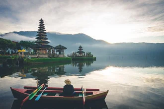 Photo art by Christian Seidenberg: man at the temple with calm water and mountains in the background
