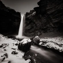 Wasserfall am Sólheimajökull: sanfte Strömung zwischen schneebedeckten Felsen