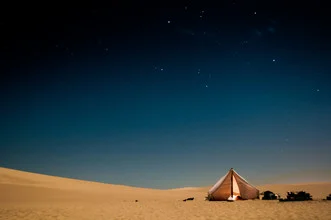 Photo art by Christian Göran: desert landscape at night with a tent and starry sky.