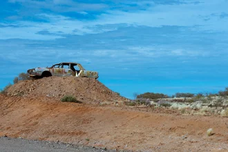 Signpost in Australia: A car wreck in the outback surrounded by dry landscape.