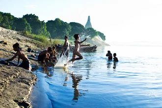 Photo art: Child joyfully jumps into the Ayravata River at dusk.