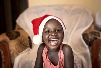 Smiling child in Uganda joyfully celebrating Christmas.