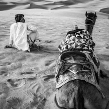 Man and camel in the desert by Sebastian Rost, soft tones and a calm atmosphere.