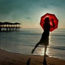 Frau mit Schirm am Strand, sanfte Farben und entspannte Atmosphäre
