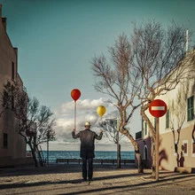Photo art: surreal man with balloons by the sea under a clear sky