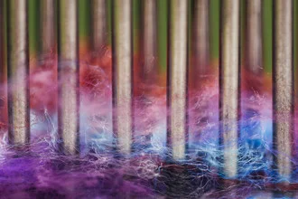 Colorful wool threads in various patterns and colors on metal rods.