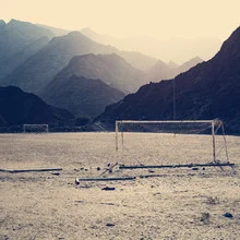 Beautiful image of a football game in the desert of Oman, surrounded by mountains.