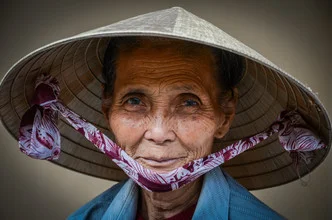 Lächelnde Frau mit Hut in Hoi An, Vietnam, bei warmem Licht