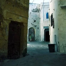 Alley in al-Jadida, Morocco, featuring a child playing on the ground.