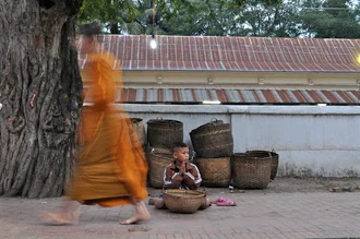 Photo of a young monk receiving alms in Luang Prabang.