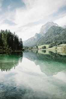 Harmonischer Blick auf den Hintersee mit reflektierenden Bergen und blauem Himmel.