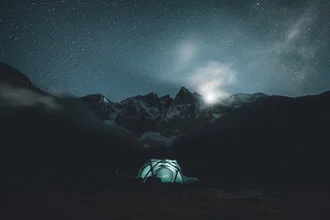 Photo art by Leo Thomas: Moonrise over the Pyrenees with tents and mountains.