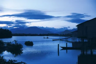 Meditation in Blau: Fischer auf ruhigem Wasser in Vietnam, entspannte Abendstimmung.