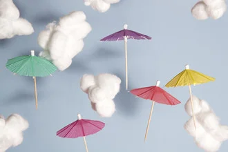 Fotokunst mit bunten Regenschirmen am Himmel, fröhliche Stimmung und tropisches Flair.