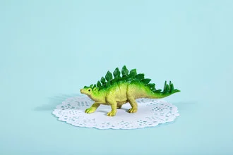 Witziger Stegosaurus aus Kunststoff, leuchtend in Türkis und Grün, Stillleben mit einem humorvollen Touch.