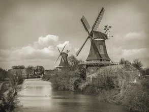 Photo art by Jörg Faißt: twin windmills by the river in northern Germany in sepia tones
