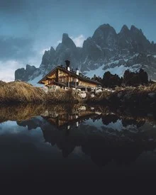 Fotokunst mit einer Hütte, die sich in den Dolomiten spiegelt, sanfte Farben und Bergstimmung.