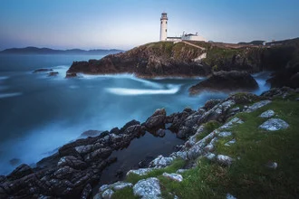 Wunderschöner Leuchtturm in Irland, umgeben von nebligem Ozean und sanften Wellen.