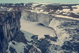 Waterfall covered in ice with a rainbow in a winter canyon