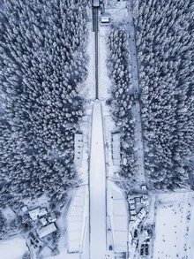 Aerial view of a ski jumping hill in Poland, surrounded by snow-covered mountains